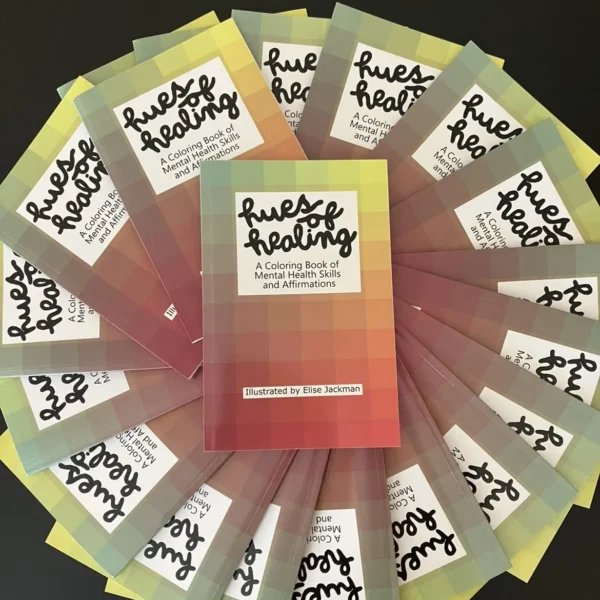 Several copies of Hues of Healing fanned out in a circle shape, with one copy sitting on top in the middle