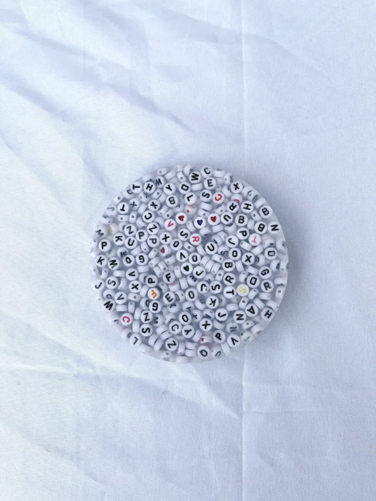 A handmade picky pad filled with various white beads imprinted with letters and symbols