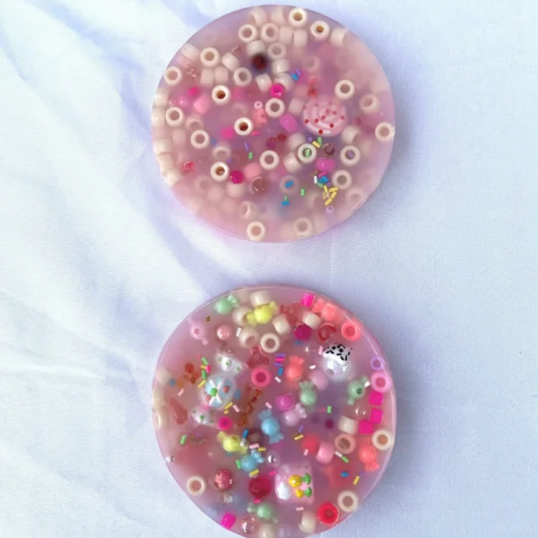 Two pink picky pads made with beads, various shapes, and mini gummy bears