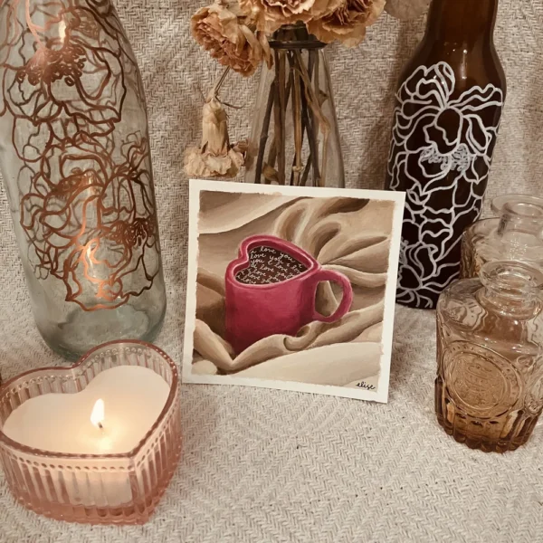 An art print surrounded with various painted bottles, flowers, and a heart shaped candle