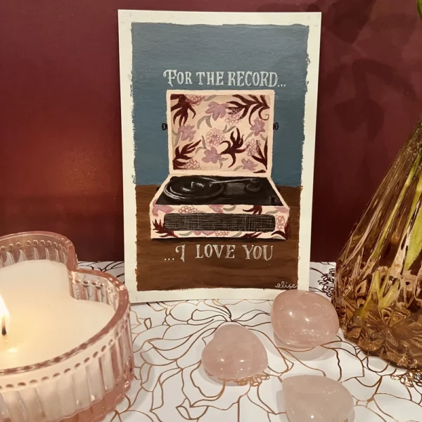 An art print of a record player surrounded with heart shaped gems and a heart shaped candle