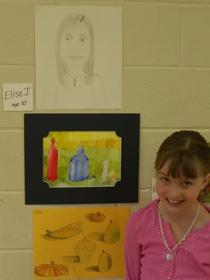 Elise Jackman as a child in front of her artwork hanging on a brick wall