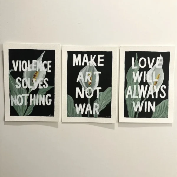 3 art prints of peace lilies, each depicting different texts, including "Violence Solves Nothing", "Make Art Not War", "Love Will Always Win"